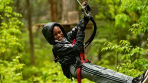 Small boy in a zipline harness smiling at the camera